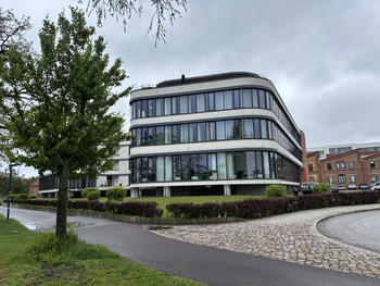 Vorderansicht des Elbeoffice in Magdeburg. Auf der linken Bildhälfte sind Bäume auf einer Wiese zu erkennen.