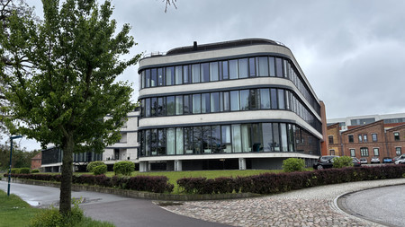 Vorderansicht des Elbeoffice in Magdeburg. Auf der linken Bildhälfte sind Bäume auf einer Wiese zu erkennen.
