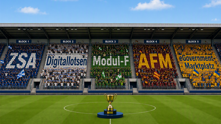 Auf dem Bild ist ein Fußballstadion mit einer Trophäe in der Mitte im WM-Fieber zu erkennen. Auf den Zuschauertribünen sind die Namen "ZSA", "Digitallotsen", "Modul-F", "AFM", und "eGovernment-Marktplatz" zu erkennen. 